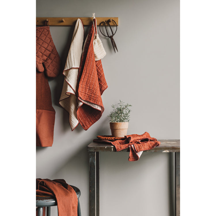 A kitchen with Heirloom's Cinnamon Stick Collection hanging on the wall, including a Mercado Tote Bag, a Double Weave Dishtowel, a Stonewash Mitt, and a Double Weave Napkin.