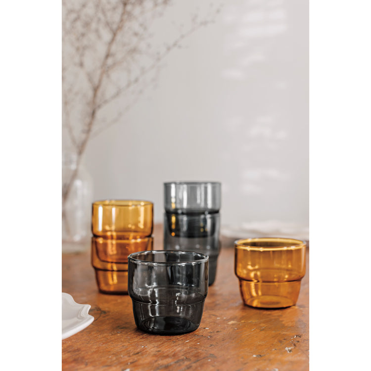 Multicolored Stacked Tumbler glasses in Smoke gray and Amber yellow sitting on a table.