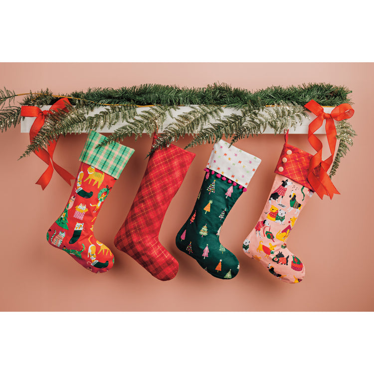 Danica Jubilee Christmas printed stockings hanging on a pink wall.