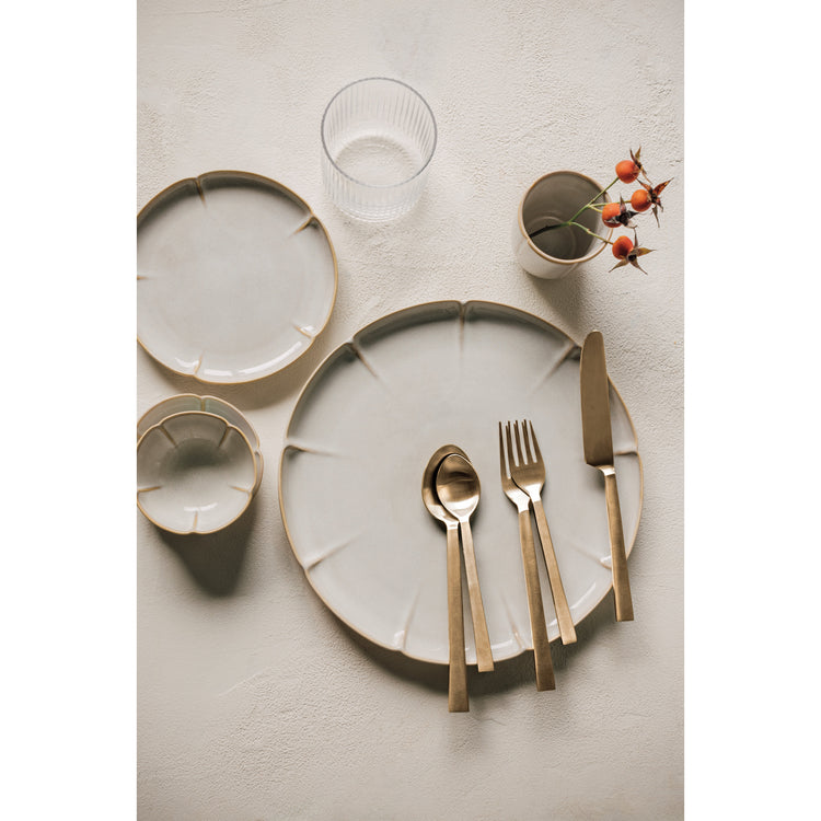 A set of Heirloom Matte Gold Edge flatware on a table with Hanami dinnerware and a Clear Fluted Tumbler glass.