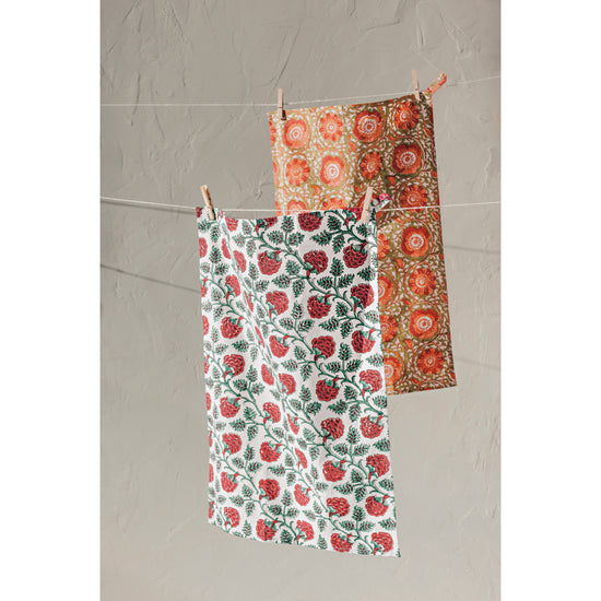 Two floral Heirloom Block Print Dishtowels in Carnation and Zinnia designs hanging on a clothesline.