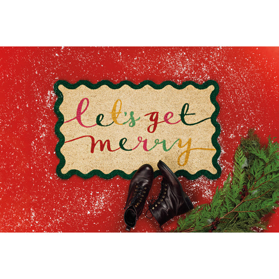 A Danica Jubilee shaped doormat with a scalloped edge from the Merry Everything Christmas collection that says Let's Get Merry in colorful cursive writing.