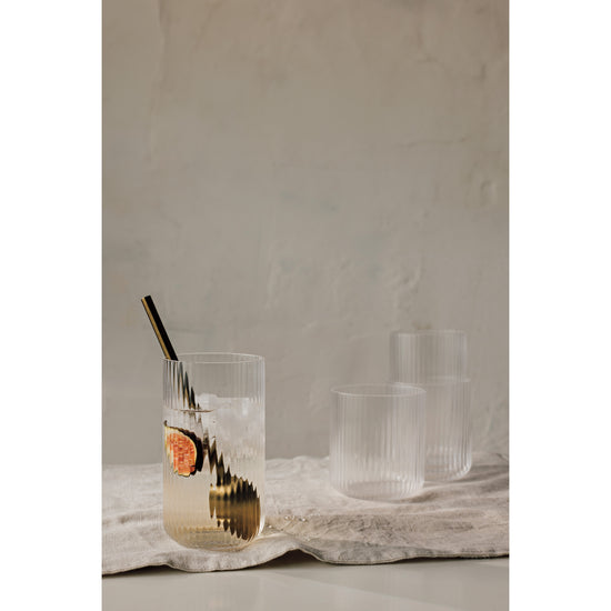 Heirloom Clear Fluted Tumbler glasses and a matte gold spoon on a table.