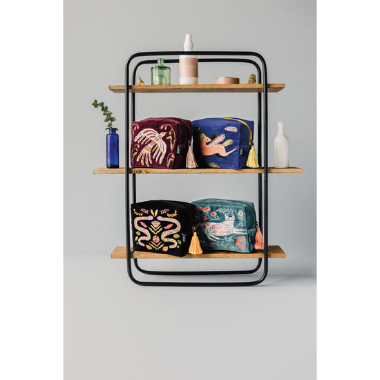A wooden shelf with a variety of Danica Studio Embroidered Pouches on it.
