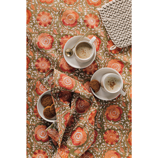 A floral Heirloom Zinnia Block Print Tablecloth and Napkin with Aquarius Oyster Mugs, an Ivory Foundation Dip Bowl, and a Dove Gray Stonewash Knit Potholder.